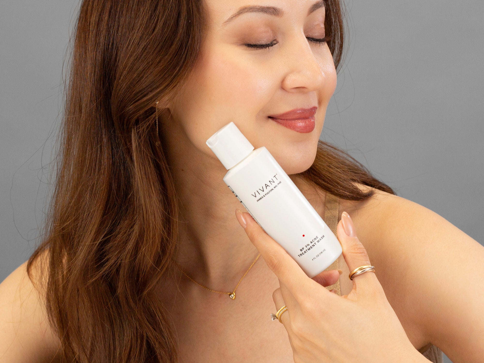 Closeup of Laziza from LAZ Skincare holding a bottle of Vivant BP 3% Acne Wash up to her face