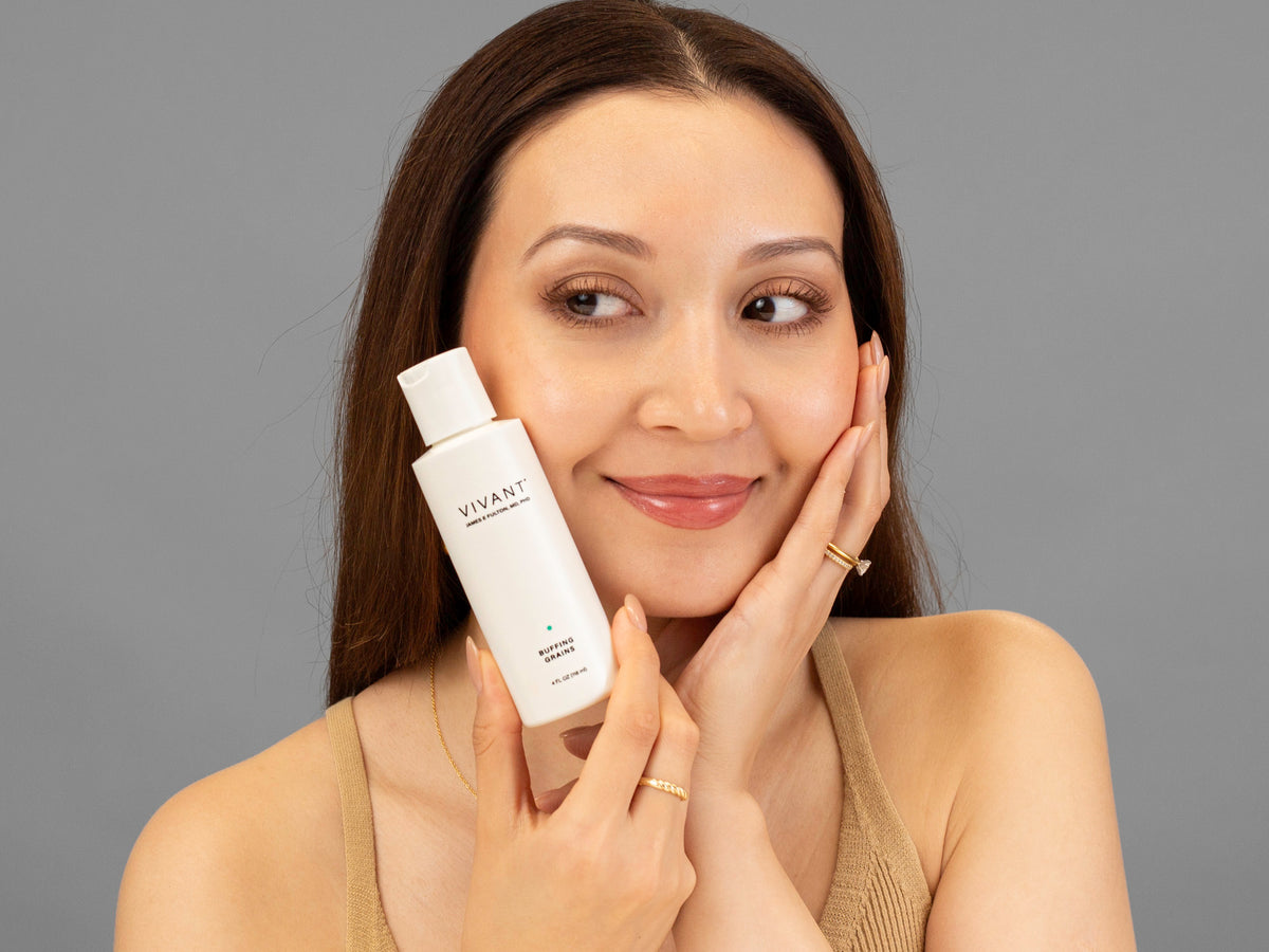 Laziza from LAZ Skincare holding a bottle of Vivant Buffing Grains up to her face