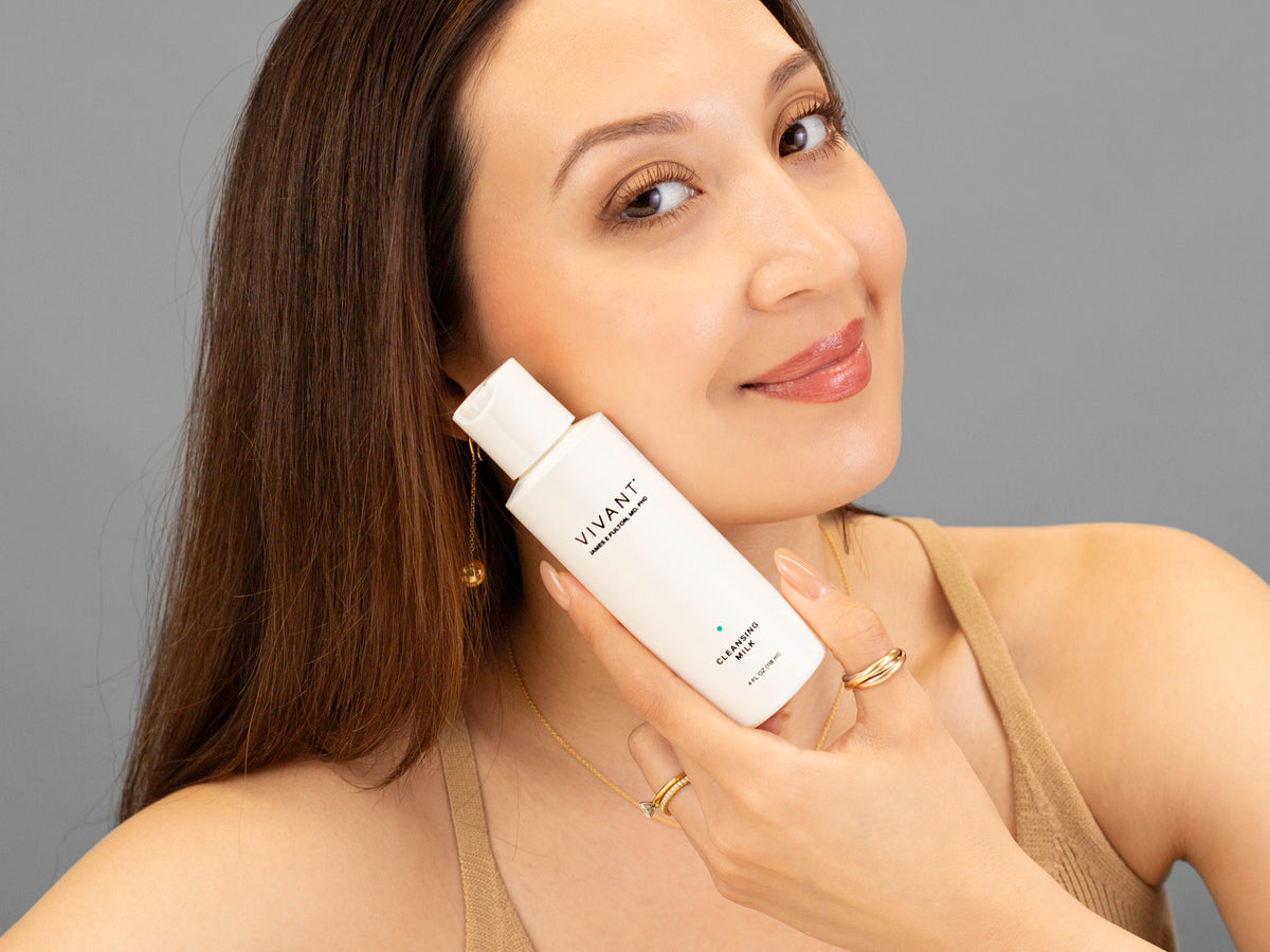 Laziza from LAZ Skincare holding a bottle of Vivant Cleansing Milk up to her face