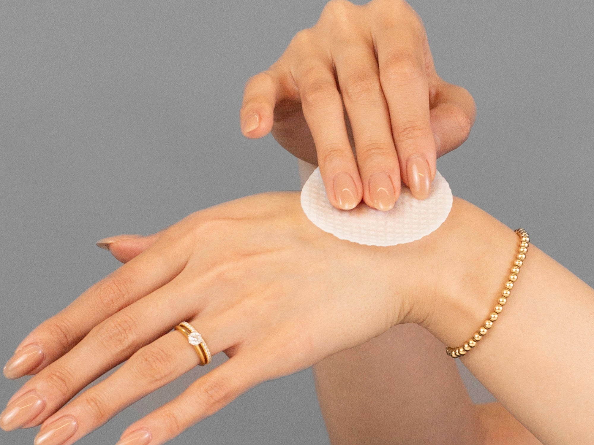 Closeup of Laziza from LAZ Skincare applying Vivant Daily Repair Pads to her hand