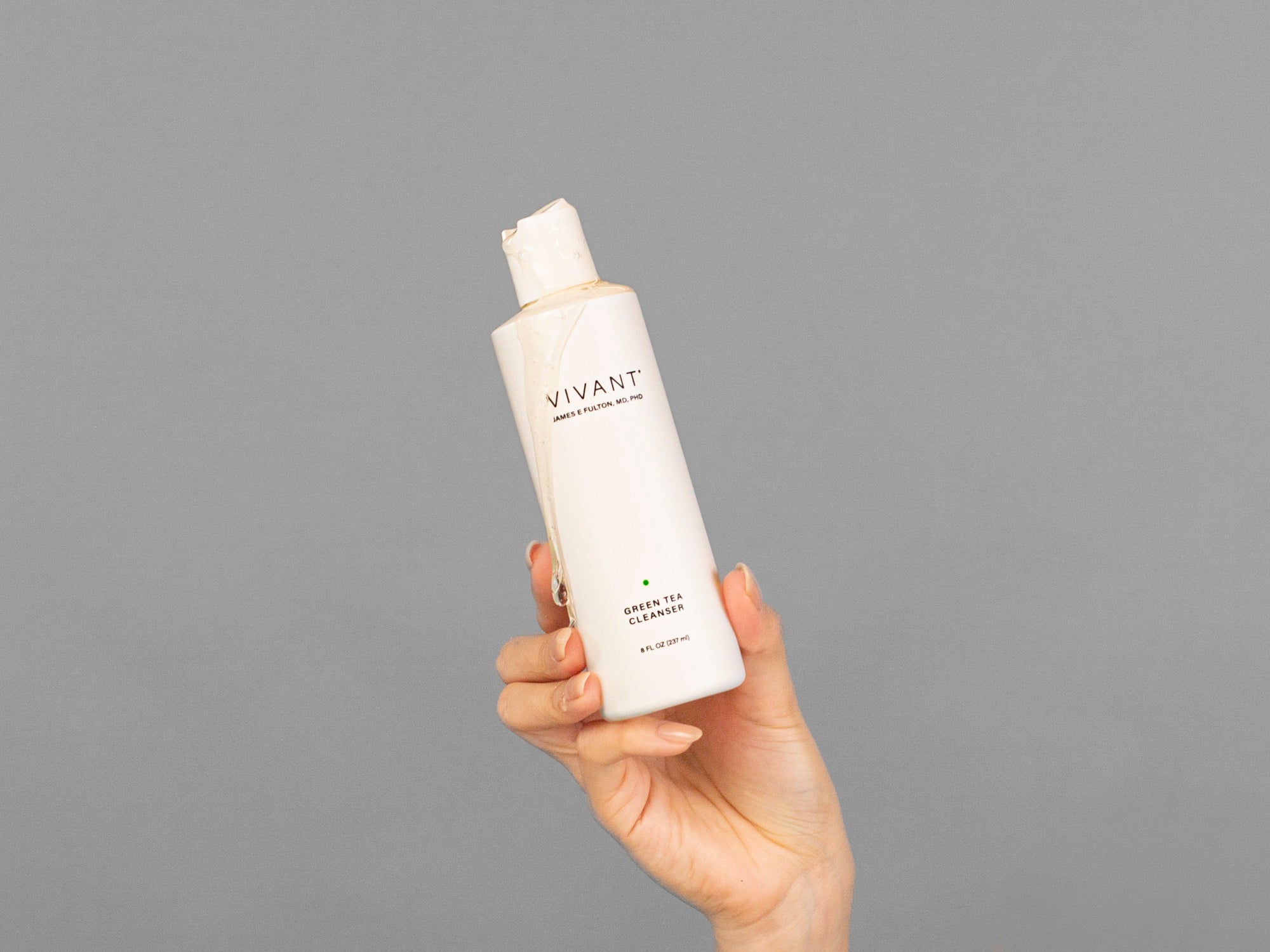 Closeup of Laziza from LAZ Skincare holding bottle of Vivant Green Tea Antioxidant Cleanser in her hand