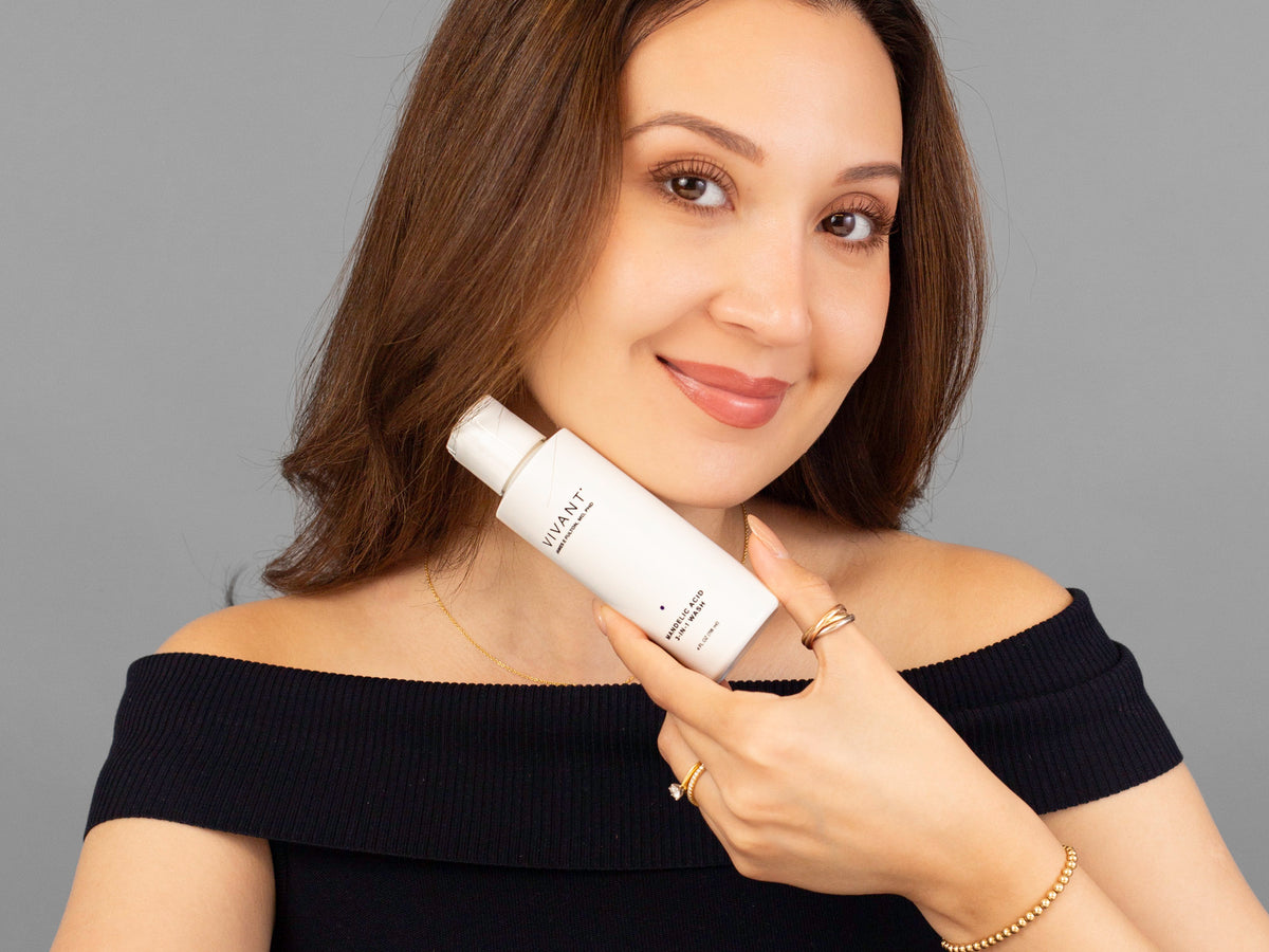 Laziza from LAZ Skincare holding a bottle of Vivant Mandelic Acid 3-in-1 Wash up to her face