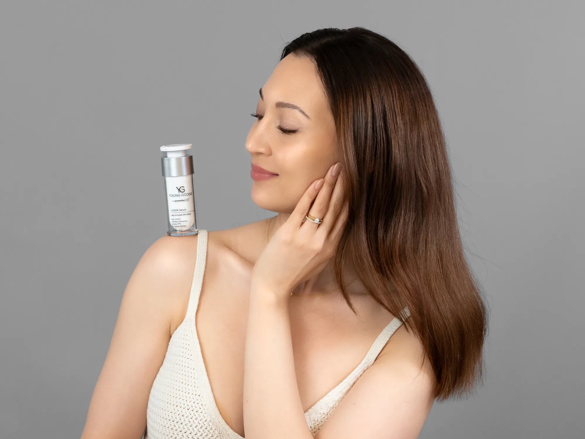 Laziza from LAZ Skincare holding a bottle of Young Goose L.A.D.R. Serum up to her face