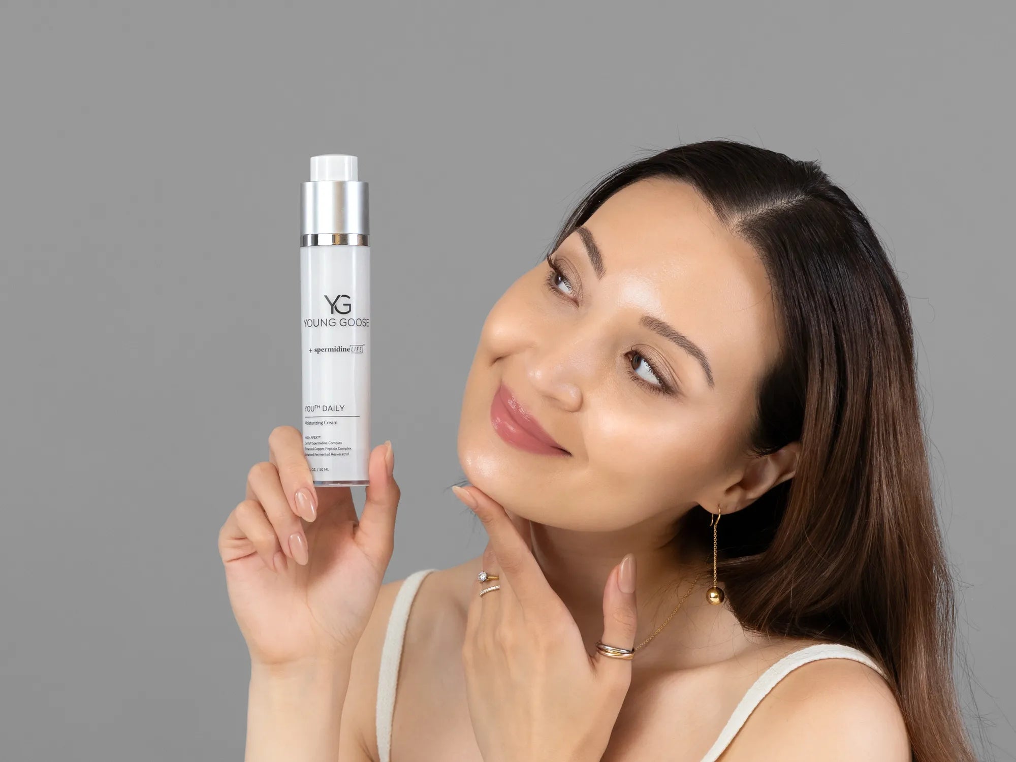 Laziza from LAZ Skincare holding a bottle of Young Goose Youth Daily up to her face