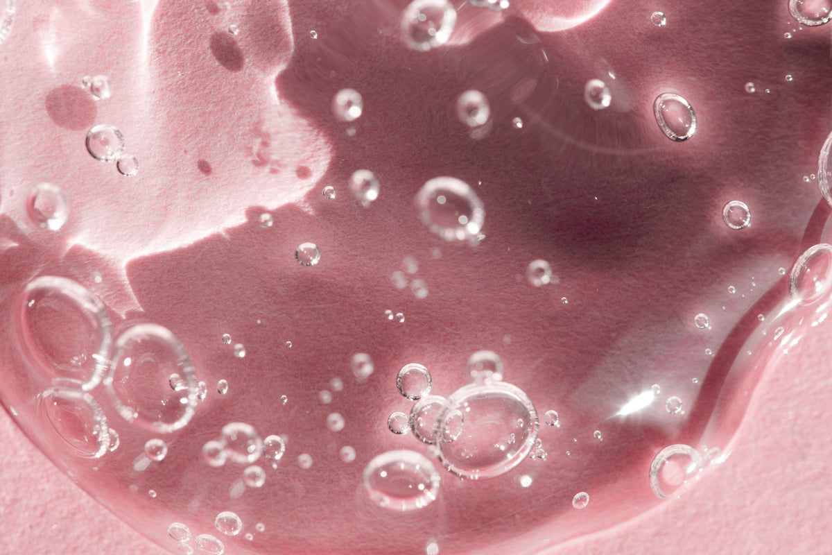 Diagram showing azelaic acid doing four jobs at once: calming redness, reducing acne bacteria, keeping pores clear and fading dark marks.